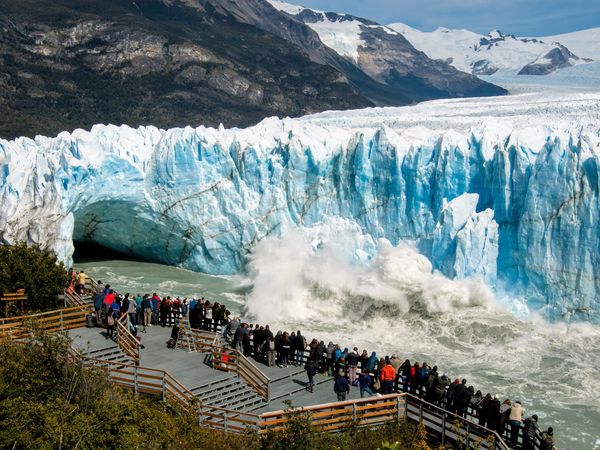 Tourists on wooden walkways witness a massive ice collapse at Glaciar Perito Moreno in El Calafate, Patagonia.