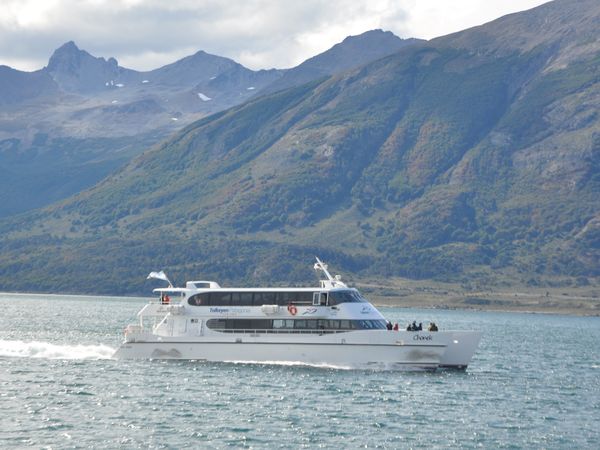 Cruise ship Chenek navigates turquoise waters beneath snow-capped mountains in Beagle Channel, Patagonia.
