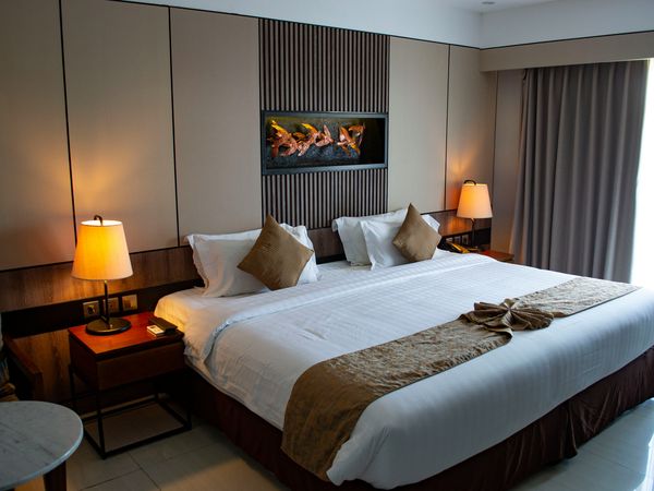 Luxury hotel bedroom with modern fireplace, white bedding, warm lighting, and contemporary decor in a South American resort.
