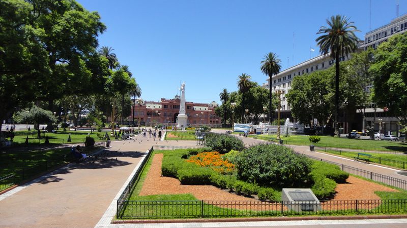 Plaza de Mayo in Buenos Aires featuring the iconic pink Casa Rosada government building surrounded by palm trees and manicured gardens.