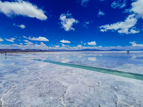 Turquoise water channels wind through the white salt flats of Salinas Grandes under a brilliant blue sky.