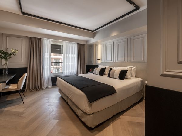 Luxury bedroom at Fierro Hotel Buenos Aires featuring a king bed, modern ceiling design, and city views from the window.
