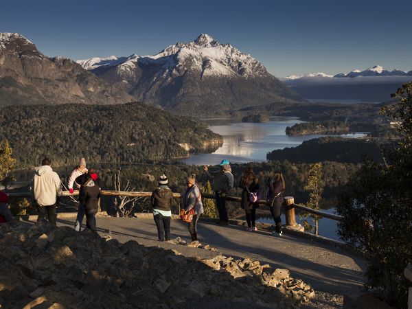 Tourists admire snow-capped mountains and pristine lakes from a scenic viewpoint in Bariloche's Circuito Grande.