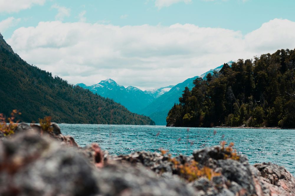 Turquoise lake surrounded by forested mountains and snow-capped peaks in Patagonia, Argentina.