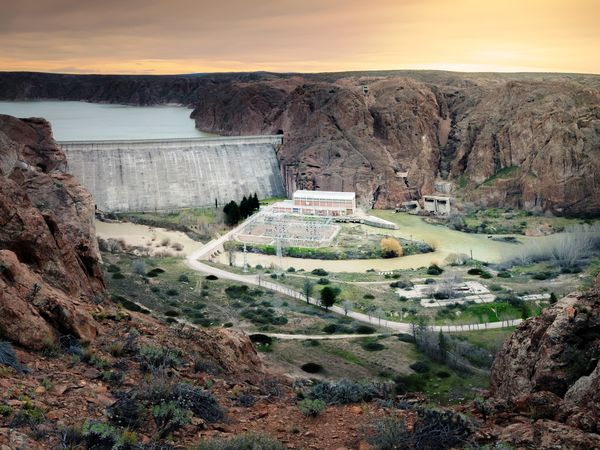 Dique Ameghino dam spans a dramatic canyon with turquoise reservoir waters in Patagonia at sunset.
