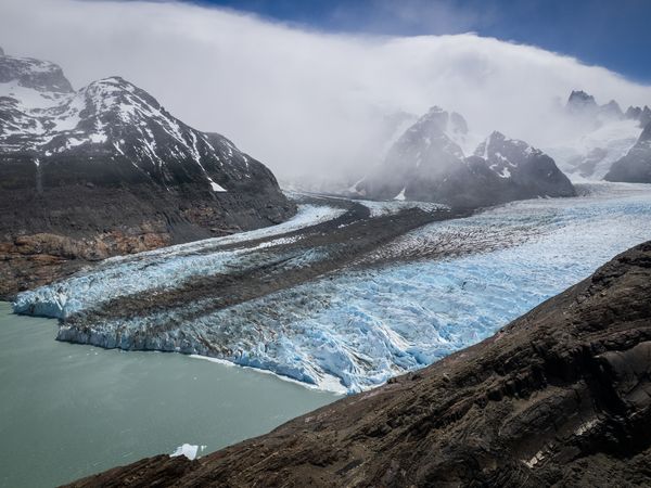 Turquoise glacial lake meets towering peaks and blue ice of Glaciar Sur in Patagonia.