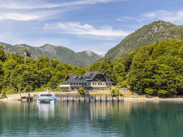 Lakeside lodge at Puerto Blest near Bariloche with turquoise waters, forested mountains, and docked boat.