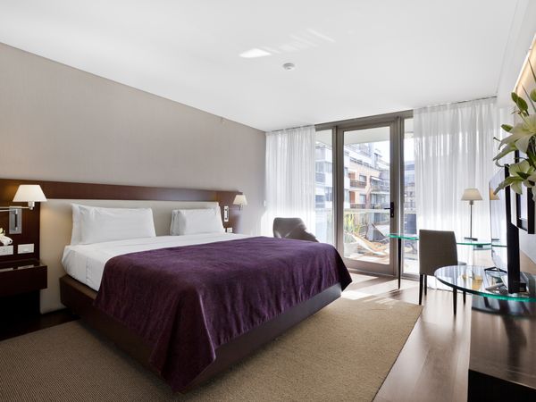 Modern luxury bedroom with purple blanket, city views through floor-to-ceiling windows, and contemporary furnishings in Buenos Aires hotel.