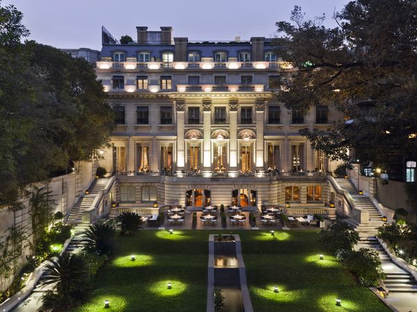 Elegant Palacio Duhau mansion illuminated at dusk with manicured gardens and classical architecture in Buenos Aires.