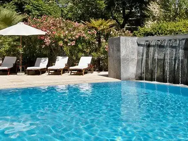 Luxury resort pool with crystal-clear blue water, lounge chairs, umbrella, and manicured gardens at Park Hyatt.