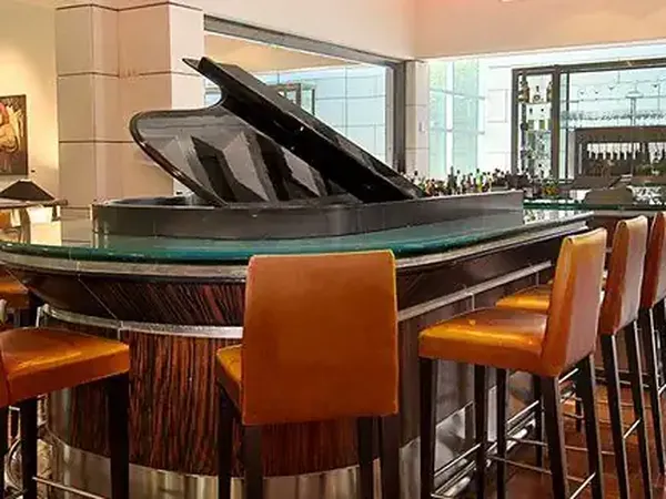 Elegant piano bar lounge at Park Hyatt with orange leather seating, grand piano, and floor-to-ceiling windows overlooking the city.