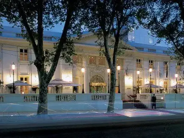 Elegant colonial-style hotel facade illuminated at dusk with manicured trees and balustrade fence in Buenos Aires.
