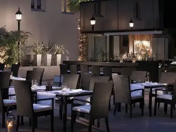 Elegant outdoor dining courtyard at Park Hyatt with candlelit tables, modern dark furniture, and ambient evening lighting.