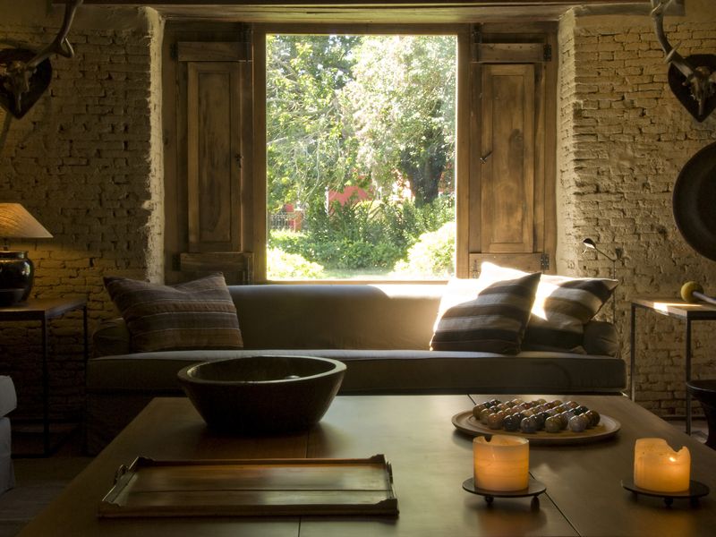 Rustic brick interior at La Bamba de Areco pulpería in Buenos Aires with traditional furnishings and garden views.