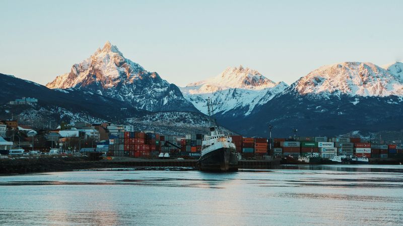 Snow-capped peaks rise behind a cargo ship docked at Ushuaia's port in Tierra del Fuego, Argentina.