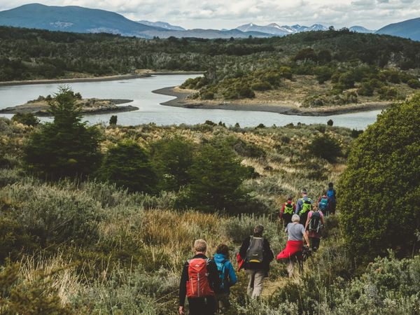 Hikers explore a scenic trail overlooking turquoise lakes and Patagonian mountains in the Lake District region.