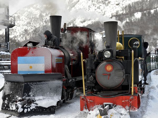 Historic steam locomotives parked in snow at Tren Fin del Mundo railway station in Ushuaia, Patagonia.