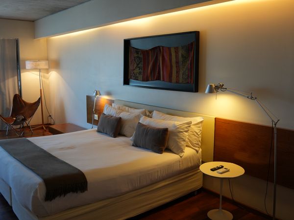 Modern hotel bedroom in Salta with warm ambient lighting, king bed, flat-screen TV, and contemporary furnishings.