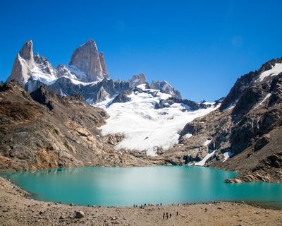 Turquoise glacial lake beneath snow-capped peaks of Mount Fitz Roy in El Chaltén, Patagonia.