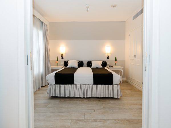 Elegant hotel suite at Fierro Buenos Aires with striped bed skirt, black and white bedding, and modern wall sconces in Recoleta.