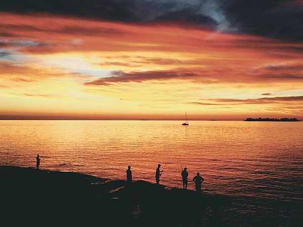 Silhouetted travelers watch a dramatic golden sunset over the Río de la Plata in Colonia del Sacramento, Uruguay.