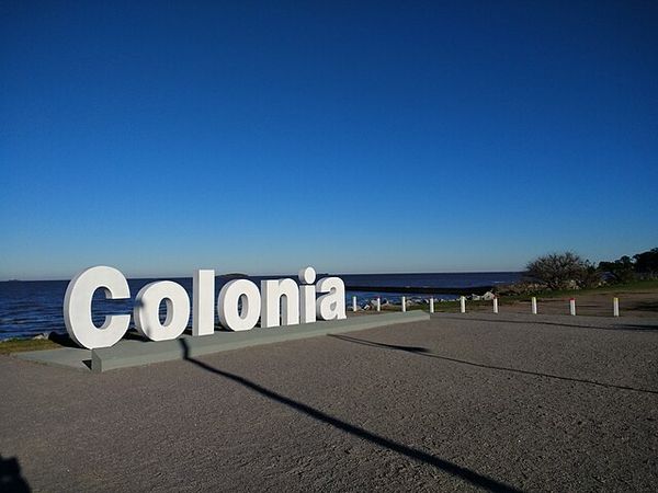 Colonia del Sacramento sign on a waterfront promenade overlooking the Río de la Plata in Uruguay.