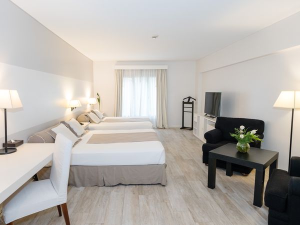 Spacious family room at Fierro Hotel Buenos Aires with twin beds, modern furnishings, and bright natural light from terrace doors.