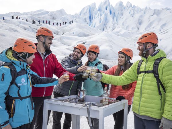 Group of hikers celebrating with drinks on a glacier during a minitrekking adventure in Patagonia.