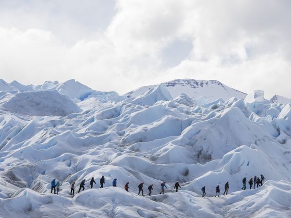Tourists hiking across the dramatic ice formations and crevasses of Perito Moreno Glacier near El Calafate, Patagonia.
