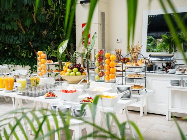 Elegant breakfast buffet at Fierro Hotel Buenos Aires featuring fresh citrus displays, pastries, and tropical plants in a bright modern setting.