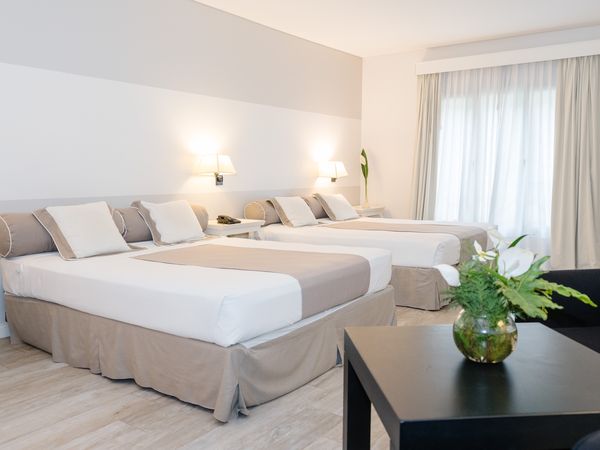 Loi Suites Recoleta family room with twin beds, neutral décor, and modern amenities in Buenos Aires.