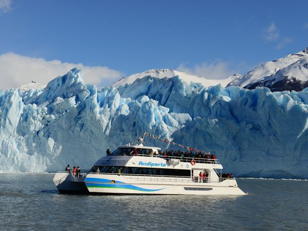 Boat tour vessel approaching the towering blue ice walls of Glaciar Perito Moreno in Patagonia, Argentina.