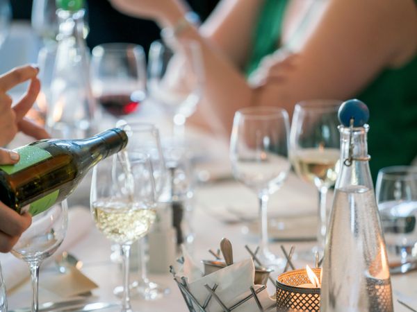 Wine tasting dinner in Buenos Aires with white wine being poured into glasses at an elegant outdoor table setting.