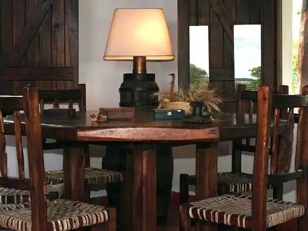 Rustic dining room at Aguapé Lodge with wooden furniture, woven chair seats, and countryside views through large windows.