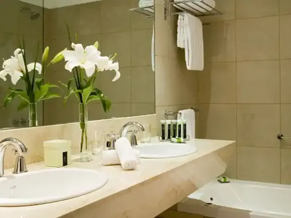 Luxury bathroom in Buenos Aires hotel with marble countertop, dual sinks, and white lilies.