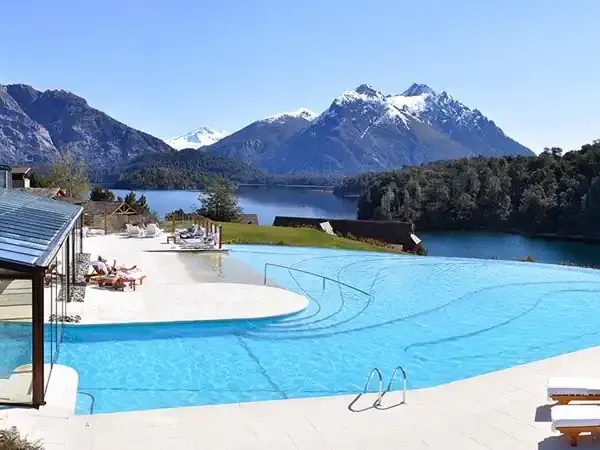 Luxury lakeside resort with infinity pool overlooking snow-capped mountains and pristine waters near Bariloche, Patagonia.