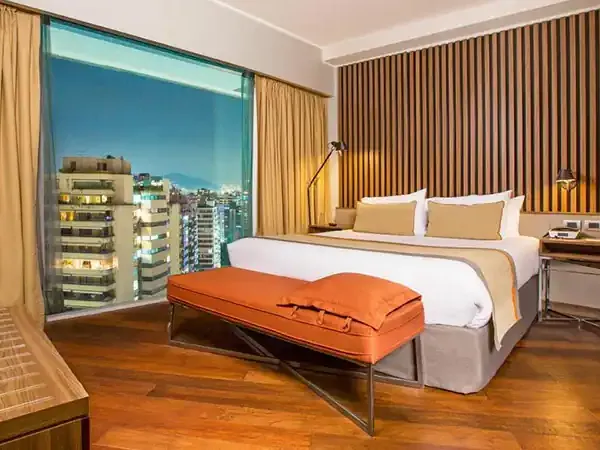 Modern hotel bedroom at DoubleTree by Hilton with city skyline views, wood flooring, and contemporary furnishings.