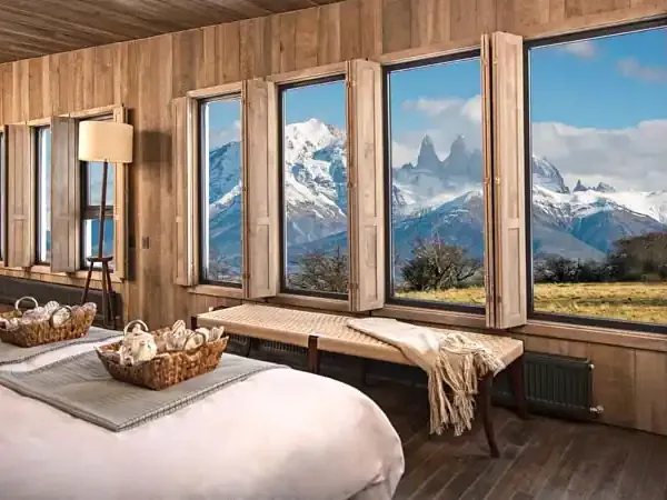 Luxury bedroom with wooden interiors overlooking snow-capped Patagonian peaks and Mount Fitz Roy in Argentine Patagonia.