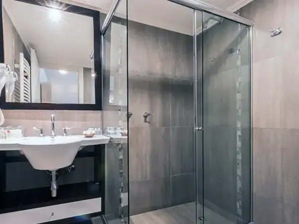 Modern bathroom with black vanity, large mirror, glass shower enclosure, and neutral tile accents at Mirador del Lago.