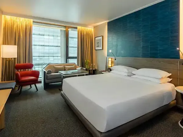 Modern hotel bedroom at Hyatt Centric Santiago with city views, contemporary furnishings, and warm lighting.