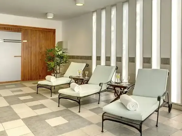 Sheraton spa relaxation area with lounge chairs, rolled towels, and natural light from floor-to-ceiling windows.