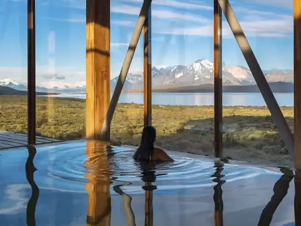 Luxury geothermal pool at Hotel Tierra Patagonia with snow-capped mountains and pristine Patagonian landscape reflecting in crystal-clear waters.