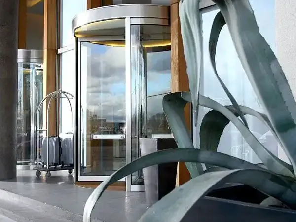 Modern revolving door entrance with sculptural metal art installation at Puerto Madero waterfront in Buenos Aires.