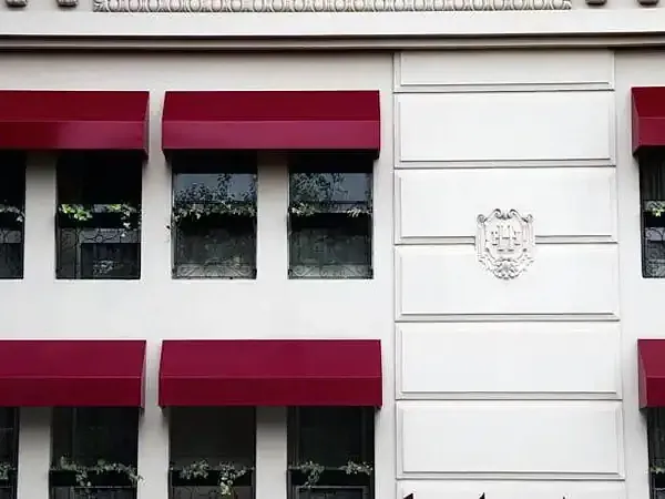 Classic Buenos Aires facade with burgundy awnings, white walls, and ornate architectural details.