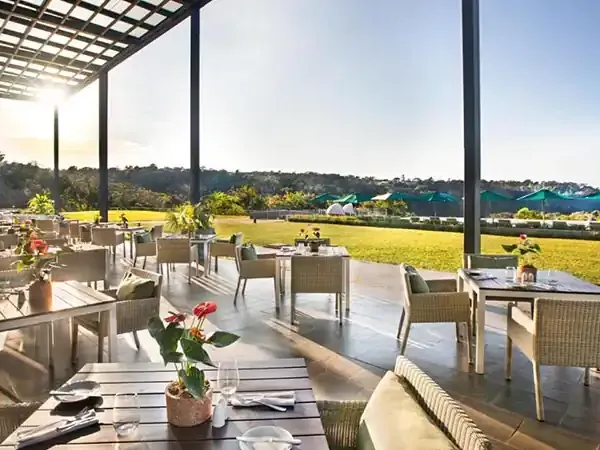 Elegant outdoor dining terrace at Gran Meliá Iguazú with panoramic views of lush green fields and tropical landscape.