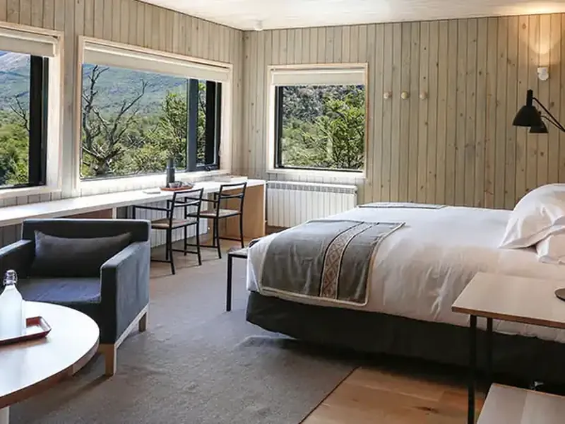 Modern luxury bedroom with panoramic windows overlooking Patagonian mountains and valleys in Chilean Chaten.