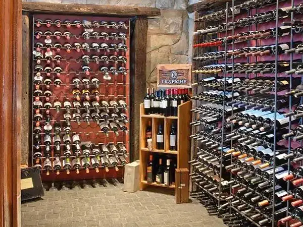Extensive wine cellar with wooden racks displaying hundreds of bottles at Incayal winery in Patagonia.