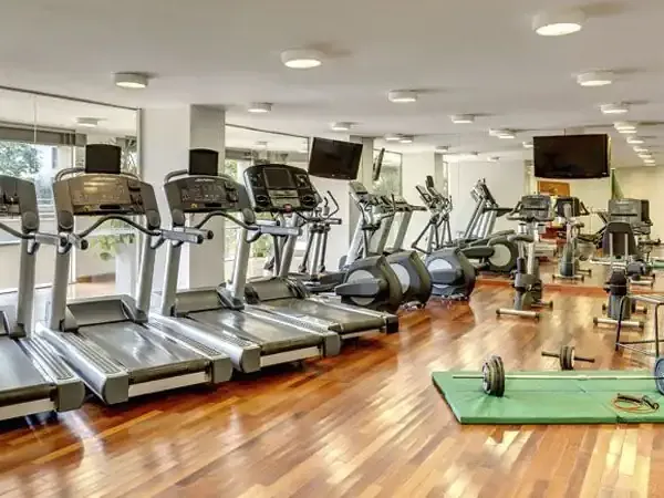 Modern fitness center at Sheraton hotel with treadmills, ellipticals, dumbbells and wooden flooring.