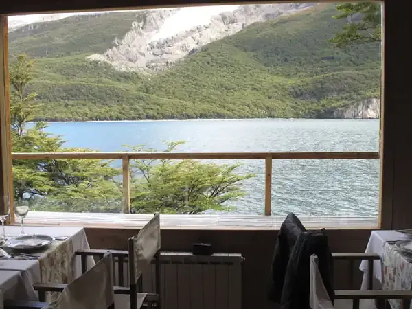 Fine dining room at Aguas Arriba Lodge overlooking a pristine Patagonian lake surrounded by forested mountains and white cliffs.
