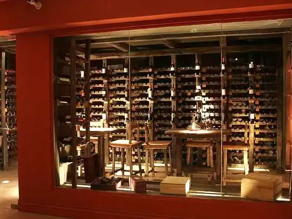 Wine shop display with wooden shelving and bottles illuminated at night in Huentalá, Patagonia.